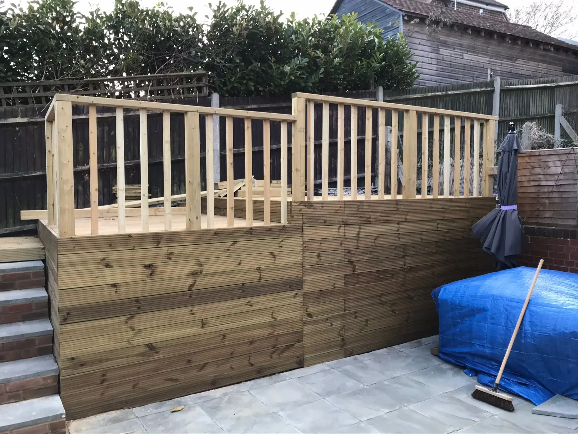 A picture of a raised wooden decking structure with timber railings under construction in a garden