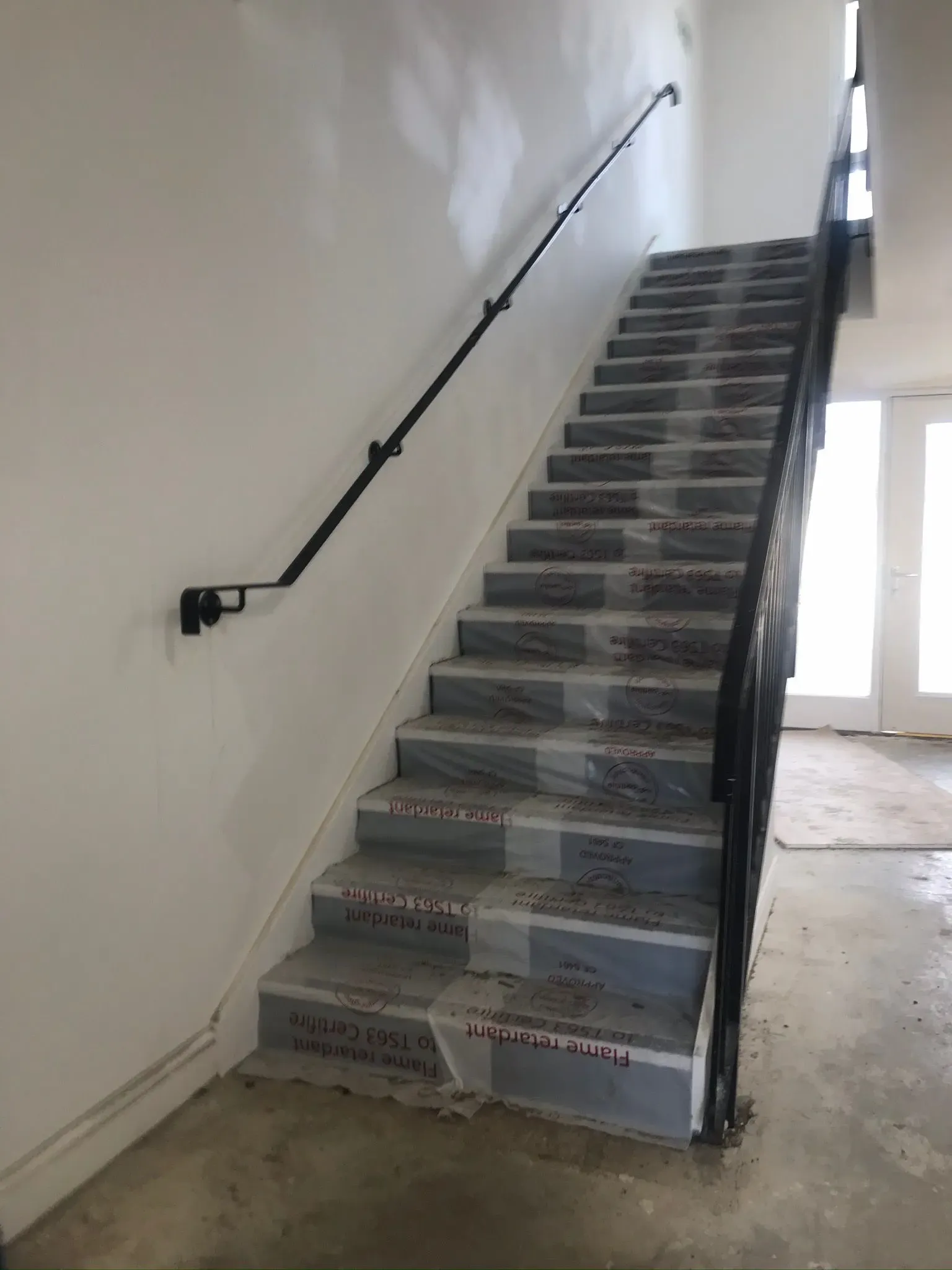 Internal staircase with protective covers and black metal handrails during an industrial unit construction project by ER3 Group LTD