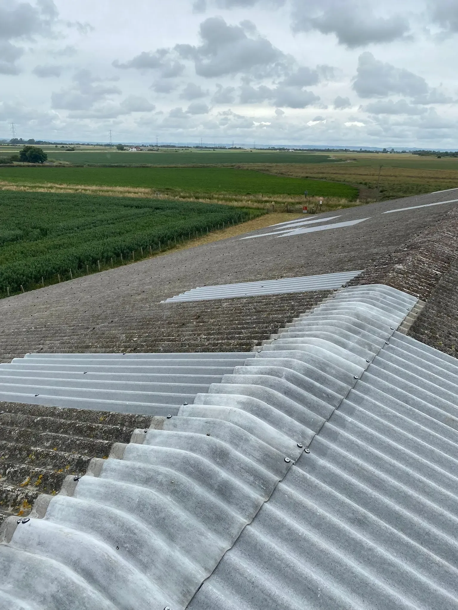 Newly installed corrugated roofing sheets and ridge caps repairing an agricultural barn roof in Sussex