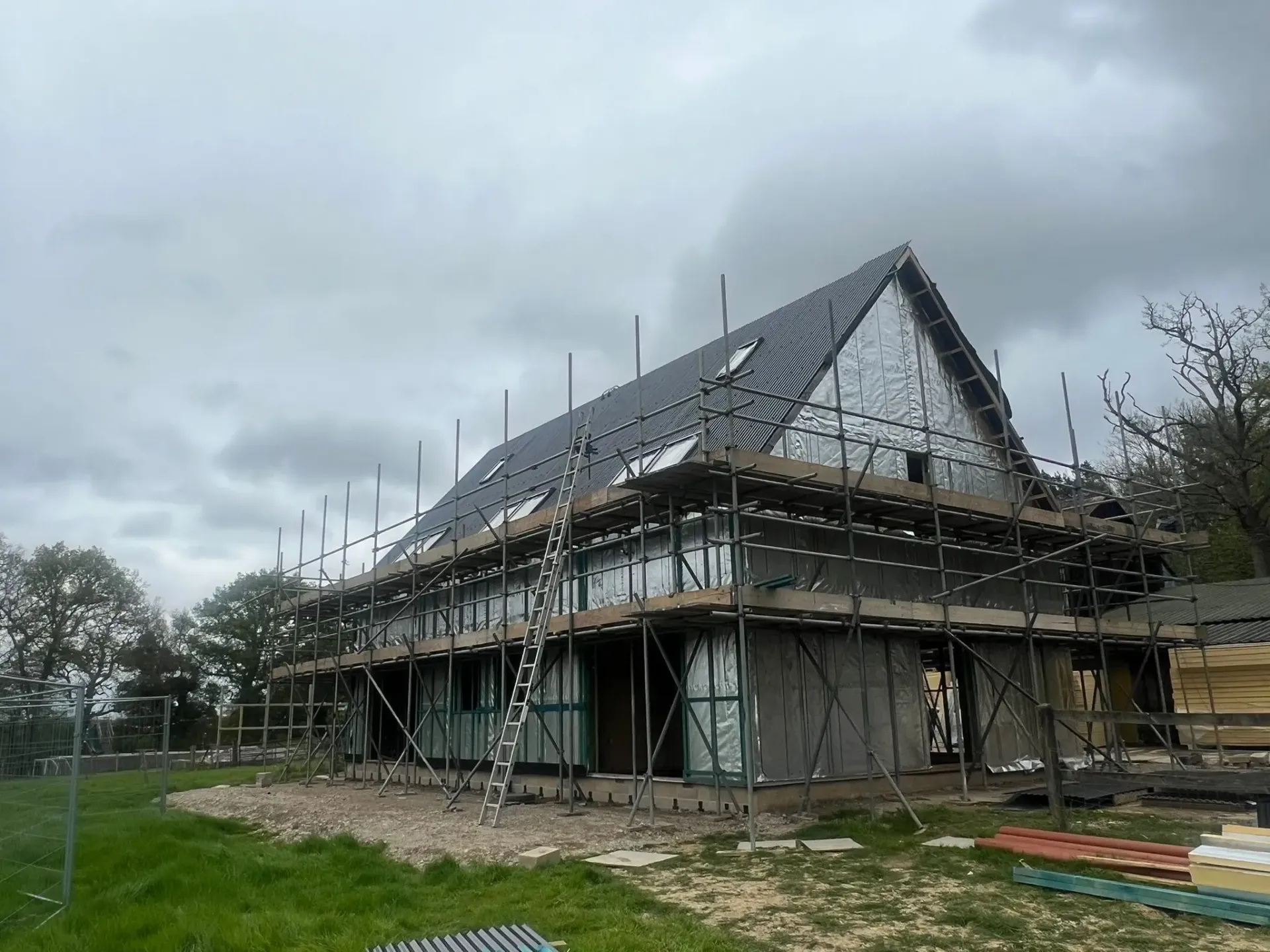 Steel-framed agricultural building under construction showing scaffolding and reflective insulation wrap installed by ER3 Group LTD